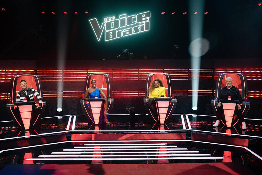 Michel Teló de preto, IZA de azul, Gaby Amarantos de amarelo e Lulu Santos de preto. Técnicos sentados nas cadeiras no palco do The Voice Brasil 11