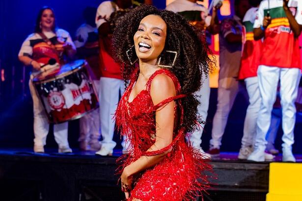 Thelma Assis de vestido brilhoso, com franjas, na cor vermelha, sorrindo, sambando durante ensaio de carnaval no Rio de Janeiro