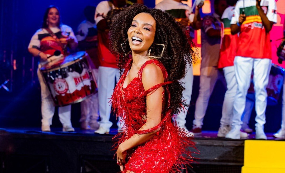 Thelma Assis de vestido brilhoso, com franjas, na cor vermelha, sorrindo, sambando durante ensaio de carnaval no Rio de Janeiro