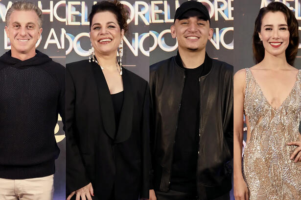 Luciano Huck de camisa preta e calça bege, sorrindo; Izabel Texeira de blazer, camisa e calça preta, cabelo preso, sorrindo; João Gomes de jaqueta de couro, chapéu, camisa e calça jeans preta, sorrindo; Marjorie Estiano de vestido brilhante, sorrindo, de cabelo preso; ambos em pé nos bastidores do Melhores do Ano da TV Globo