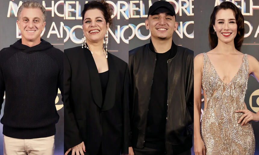 Luciano Huck de camisa preta e calça bege, sorrindo; Izabel Texeira de blazer, camisa e calça preta, cabelo preso, sorrindo; João Gomes de jaqueta de couro, chapéu, camisa e calça jeans preta, sorrindo; Marjorie Estiano de vestido brilhante, sorrindo, de cabelo preso; ambos em pé nos bastidores do Melhores do Ano da TV Globo