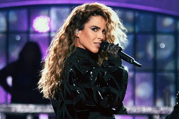 Wanessa com look preto brilhoso, cabelo ondulado, segurando um microfone durante performance no Música Boa Ao Vivo, do Multishow