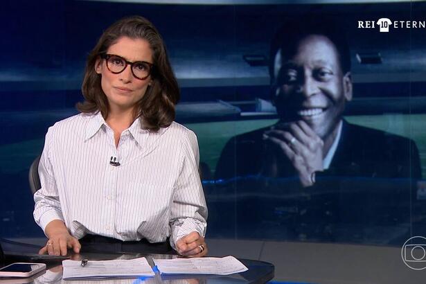 Renata Vasconcellos no cenário do Jornal Nacional para a cobertura da morte do Rei Pelé, no canto superior esquerdo está o logo especial Rei 10 Eterno