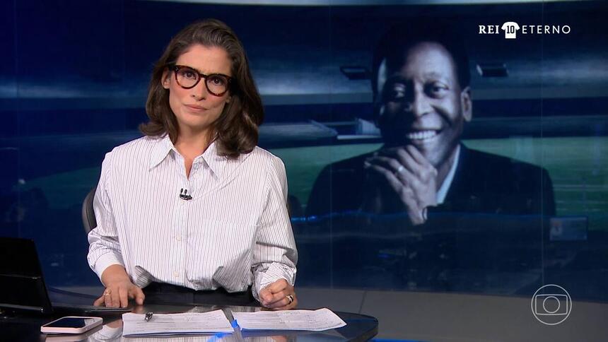 Renata Vasconcellos no cenário do Jornal Nacional para a cobertura da morte do Rei Pelé, no canto superior esquerdo está o logo especial Rei 10 Eterno