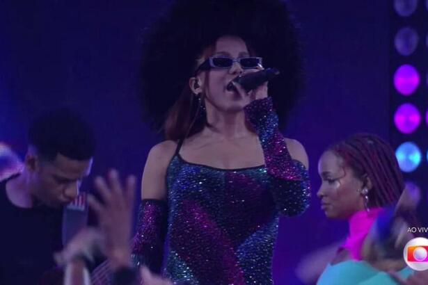 Anitta com óculos escuros com o microfone nas mãos.