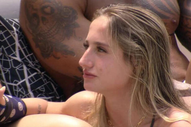 Bruna Griphao na área externa do BBB, sentada e conversando ao lado de outros brothers