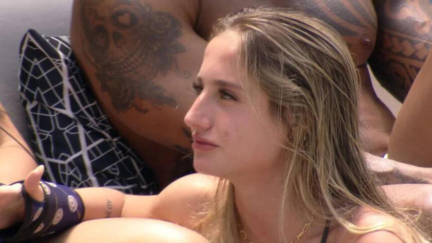 Bruna Griphao na área externa do BBB, sentada e conversando ao lado de outros brothers