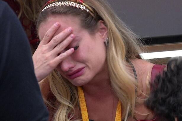 Bruna Griphao com a cabeça baixa, mão no rosto e chorando, sentada em um dos quartos do BBB 23
