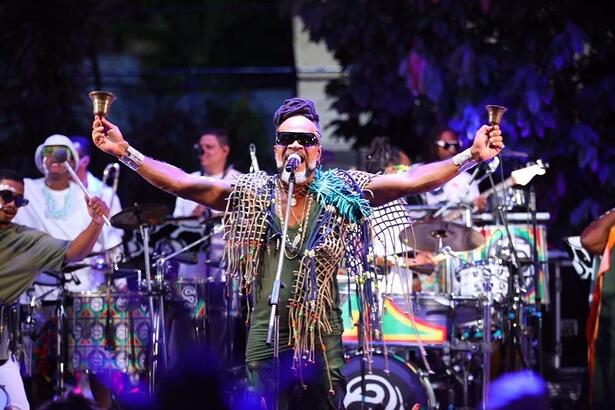 Carlinhos Brown com look animal-print, com os braços abertos durante ensaio de verão da Timbalada