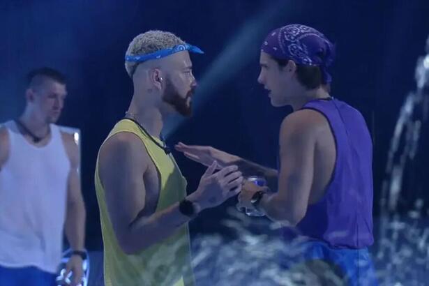 Fred e Gabriel durante a festa do BBB 23. Fred está vestido com uma camiseta amarela e uma badana na cabeça. Gabriel com uma camiseta azul e um copo na mão.