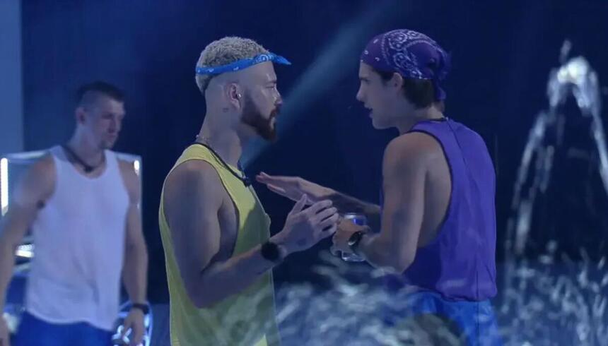 Fred e Gabriel durante a festa do BBB 23. Fred está vestido com uma camiseta amarela e uma badana na cabeça. Gabriel com uma camiseta azul e um copo na mão.