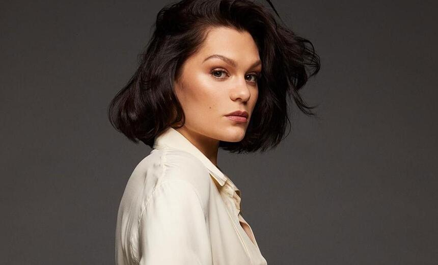 Jessie J de camisa social branca, com cabelo solto, de perfil, com semblante sério durante ensaio fotográfico