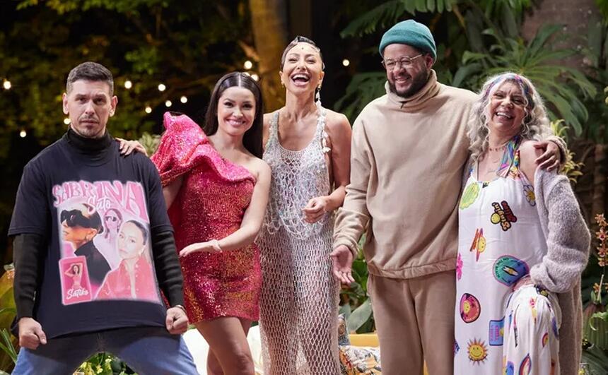 João Vicente de camisa preta e calça jeans, sorrindo, segurando a camisa; Juliette sorrindo, de vestido rosa; Sabrina Santo de vestido decotado branco, sorrindo; Emicida de toca verde com camisa e calça bege, sorrindo; Aristides Fontenelle de look branco com estampa em amarelo e vermelho durante gravação do Saia Justa