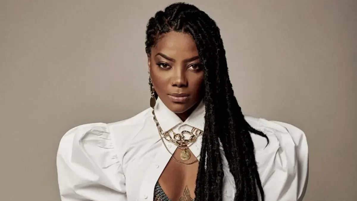 Ludmilla, em foto posada, utilizando uma roupa branca e deixando as traças à frente do ombro
