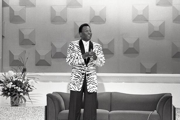 Pelé de pé, vestido com blazer branco e preto e calça preto, em participação no programa da Hebe, no SBT.