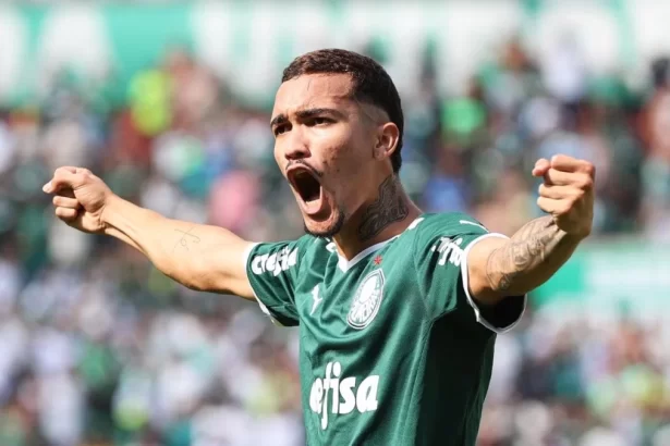 Jogador Ruan Ribeiro, com os braços abertos, comemorando um gol com a camisa do Palmeiras