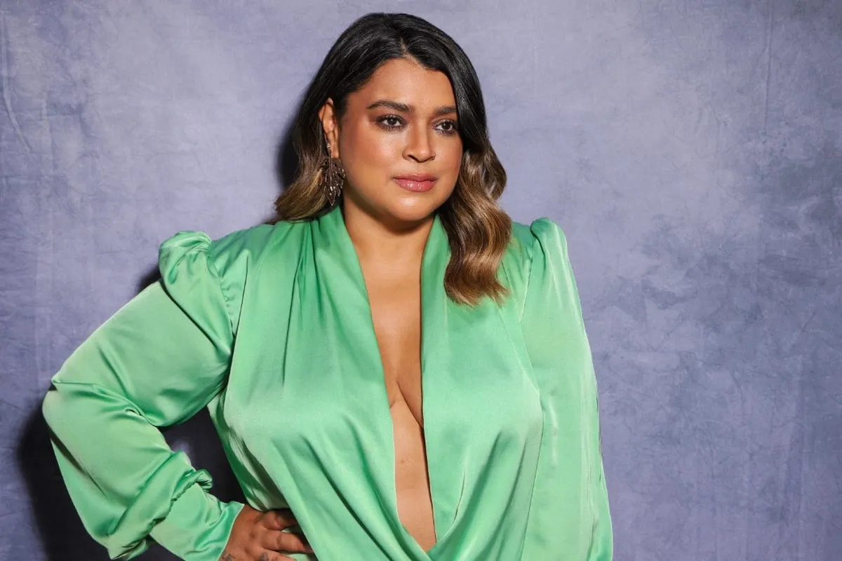 Petra Gil com uma roupa verde, em foto posada com a mão na cintura