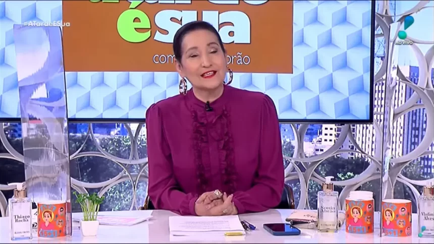 Sonia Abrão com uma roupa roxa, sentada na bancada do A Tarde é Sua