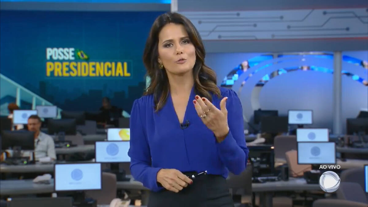 Adriana Araújo de blusa azul na redação do Jornal da Record transmitindo a posse de Jair Bolsonaro