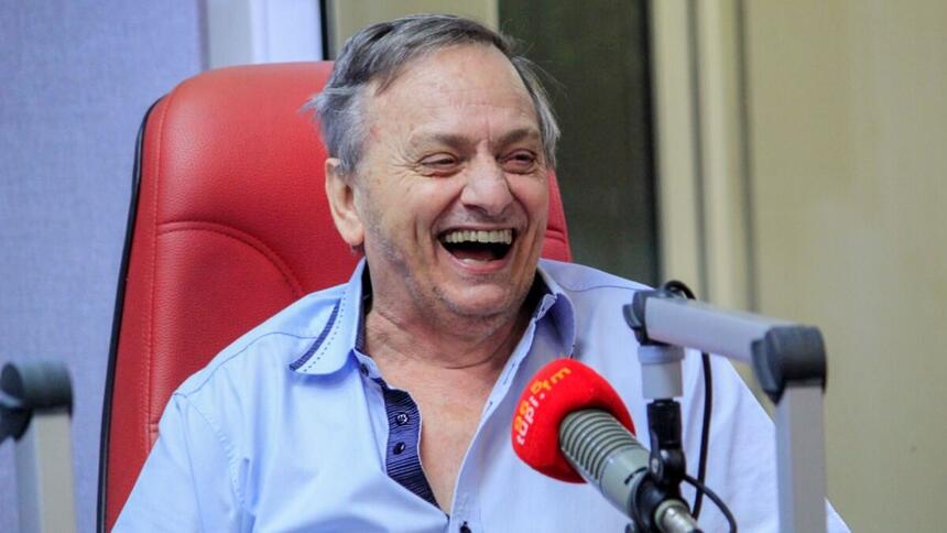 Gilson Ricardo, com um sorrido aberto no rosto, em trecho de um programa na Rádio Tupi