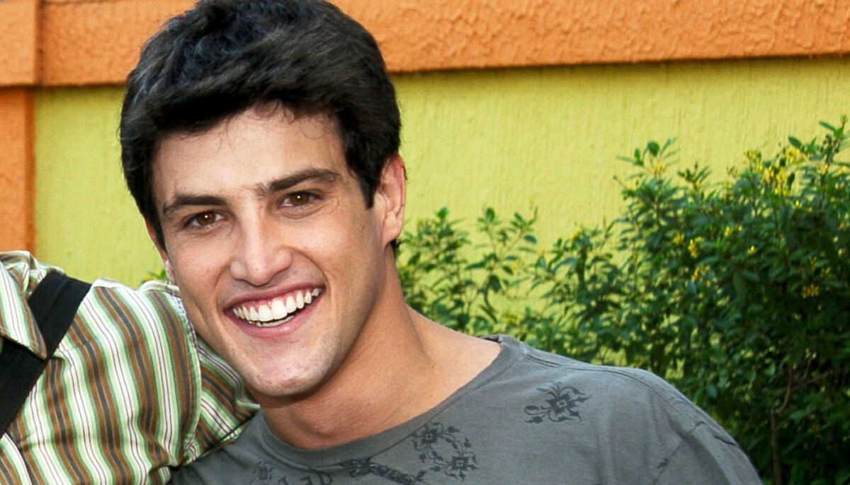 Alexandre Slaviero de camisa cinza, sorrindo, durante gravação de Malhação, da TV Globo