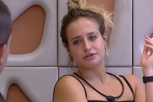 Bruna Griphao de regata preta, cabelo preso, segurando um cigarro, sentada na varada da casa do BBB 23