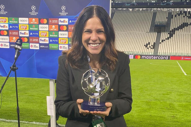 Clara Albuquerque segurando um troféu em mãos, em trecho de uma cobertura em um estádio na Itália