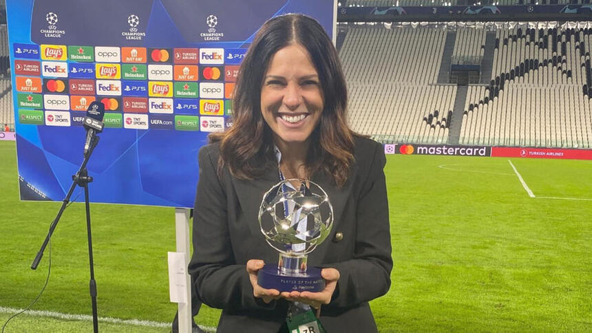 Clara Albuquerque segurando um troféu em mãos, em trecho de uma cobertura em um estádio na Itália