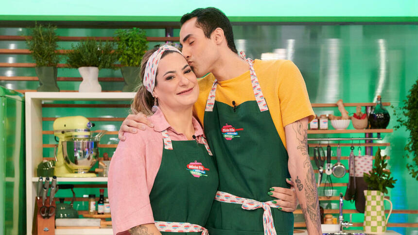 Douglas Souza e Elisangela, sua mãe, abraçados, em trecho do reality Minha Mãe Cozinha Melhor Que a Sua, na cozinha verde