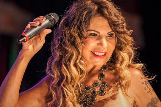 Elba Ramalho sorrindo, segurando o microfone durante show