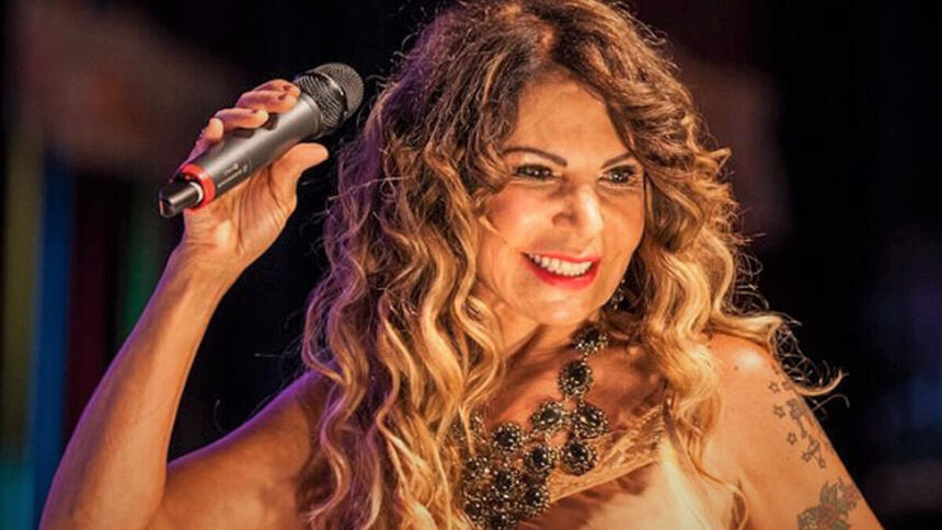 Elba Ramalho sorrindo, segurando o microfone durante show