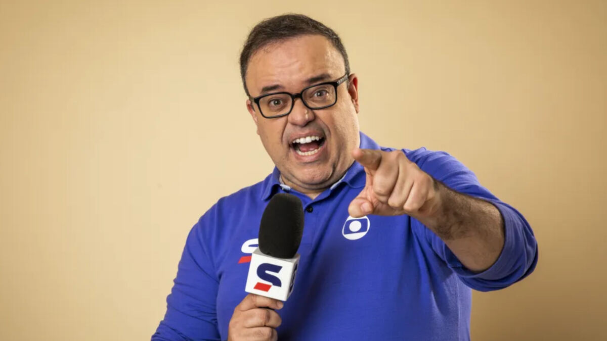 Everaldo Marques com um microfone da Globo em mãos e apontando o dedo para a câmera, em foto de divulgação e posada