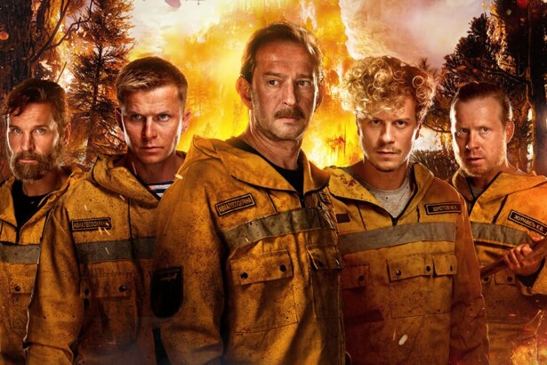 Homens com fardas de bombeiros sujos em meio a uma mata pegando fogo em cena do filme Heróis de Fogo