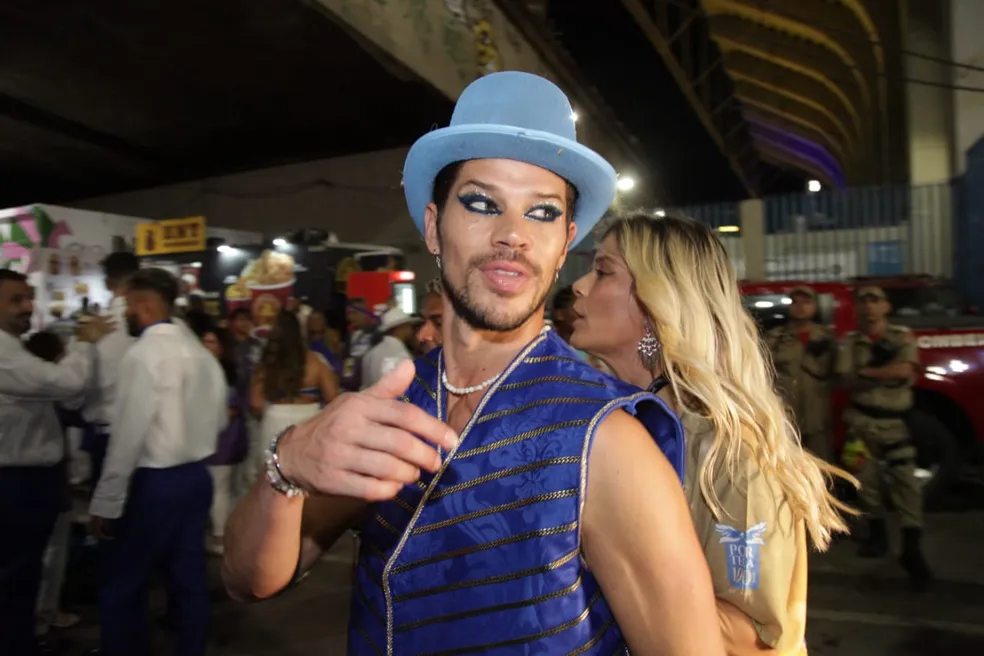 José Loreto de chapeu e look azul, acenando para fotografos em camarote no rio de janeiro