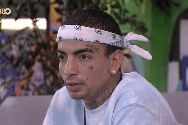 MC Guimê de bandana e camisa branca, sentado no sofá, na varanda do BBB 23