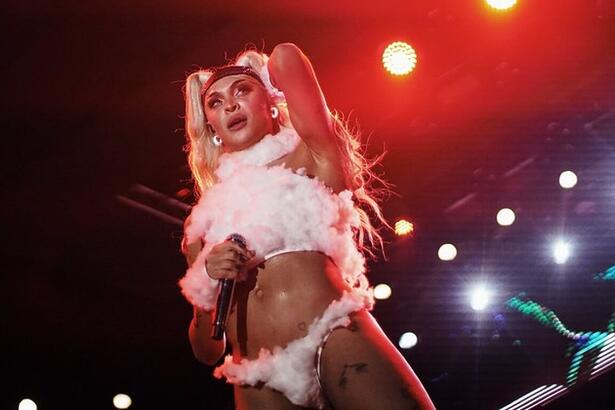 Pabllo Vittar com top branco e calcinha com plumas branca durante show em recife