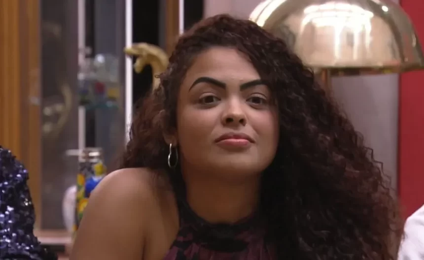 Paula olhando pra frente, sentada, cabelo solto, durante eliminação no BBB 23