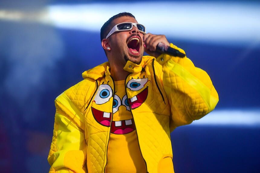 Pedro Sampaio com jaqueta e camisa do bob esponja, oculos de sol, segurando o microfone