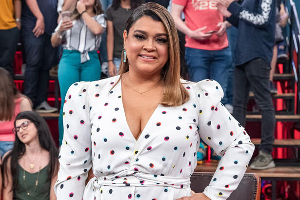 Preta Gil em foto posada, com as mãos na cintura, utilizando um vestido brando de bolinhas