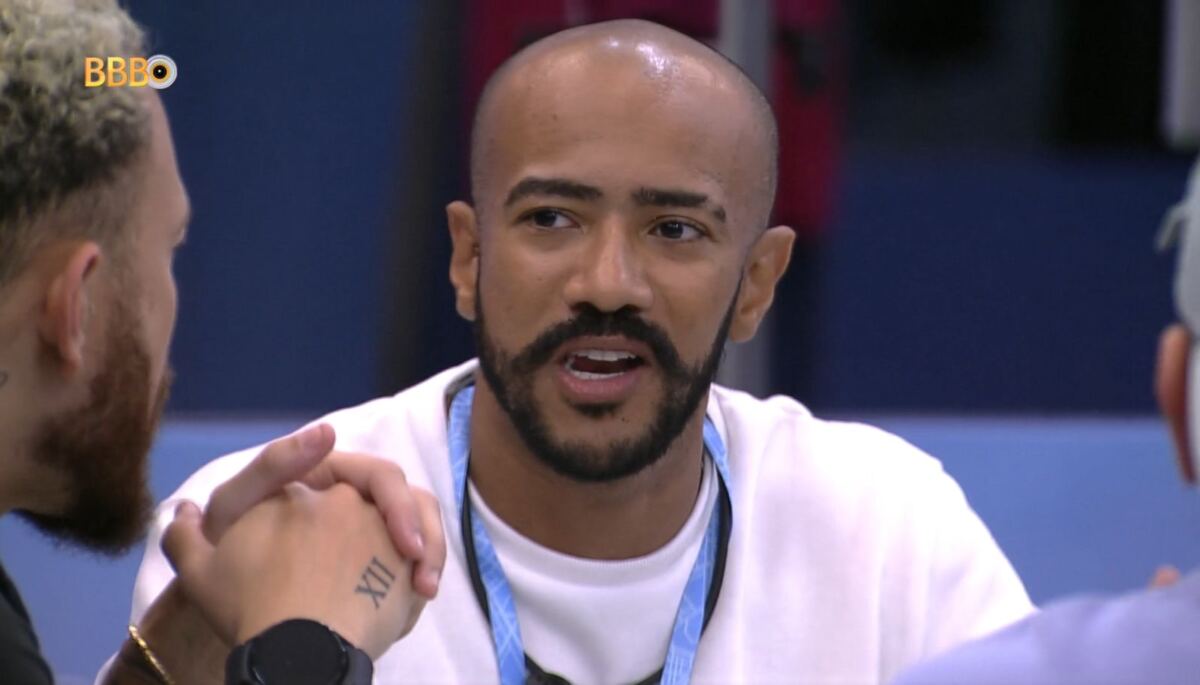 Ricardo sentado olhando para Fred com a boca aberta