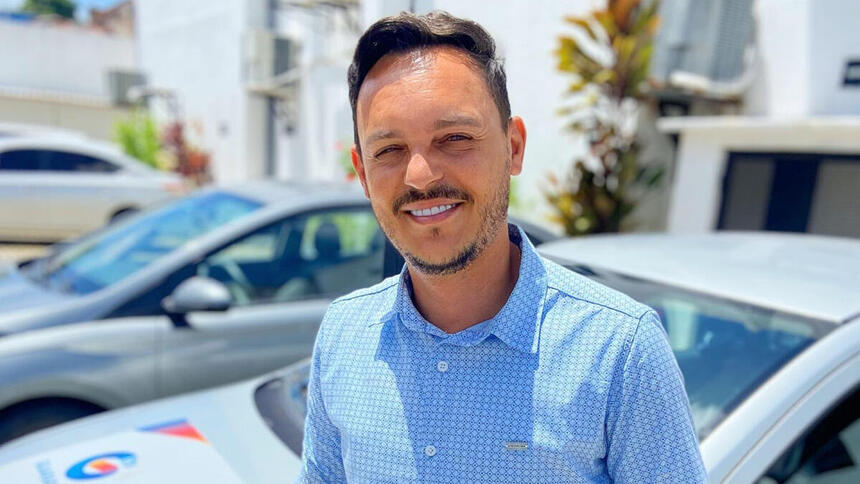 Rodrigo de Luna em frente a um carro de polícia, em foto posada, em uma cobertura na delegacia