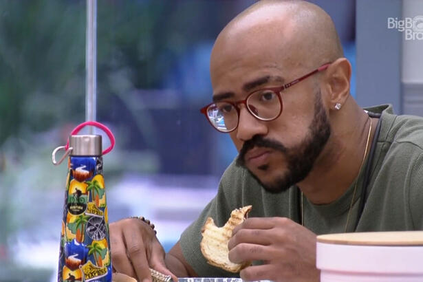 Ricardo comendo pão na cozinha do BBB 23