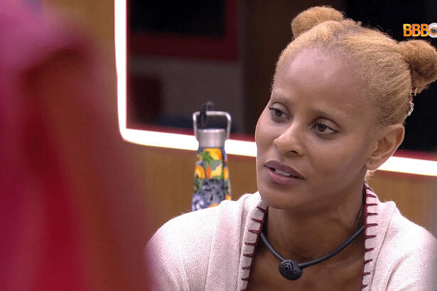 Aline Wirley de cabelo preso, camisa branca, sentada em um dos espaços da casa do BBB 23