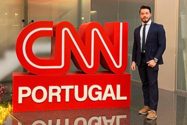 Alisson Negrini posando em frente ao logo da CNN Portugal, na sede da emissora