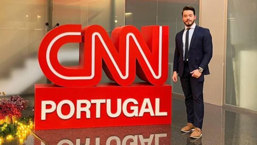 Alisson Negrini posando em frente ao logo da CNN Portugal, na sede da emissora