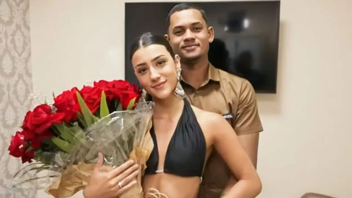 Bia Miranda e Gabriel Roza, abraçados em foto posada. Ela segura um arranjo de rosas