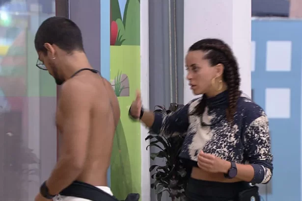 Gabriel Santana de bermuda branca, sem camisa, de perfil, andando na frente de Domitila durante conversa no jardim do BBB 23