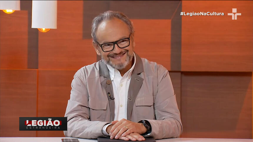 Ernesto Paglia sentado na bancada do programa Legião Estrangeira, na TV Cultura