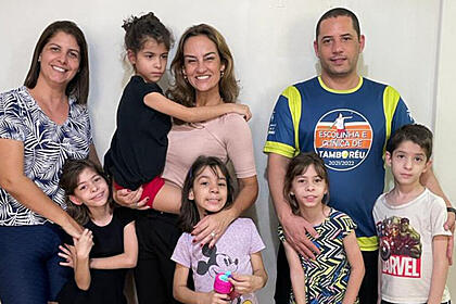 Fernanda Graell posando ao lado de um casal de pais e os seus quíntuplos gêmeos, nos batidores do Globo Repórter