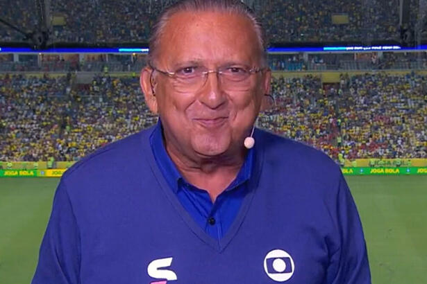 Galvão Bueno nos bastidores de uma transmissão da Globo, com um estádio ao fundo